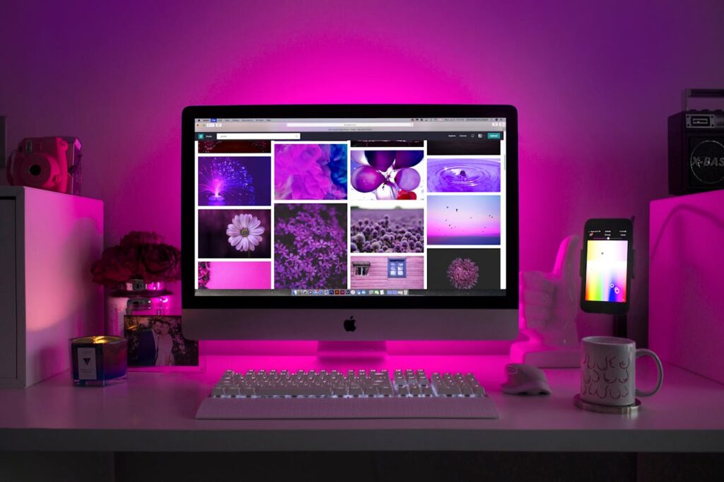 pexels-photo-1779487 Modern desk setup with neon lighting and a desktop computer displaying colorful images.